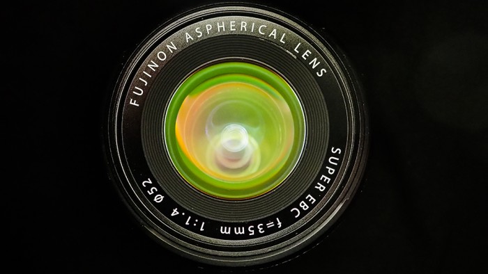 Front view of a Fujinon 35mm f/1.4 aspherical lens with colorful reflections on the front element. Front view of a Fujinon 35mm f/1.4 aspherical lens with colorful reflections on the front element.